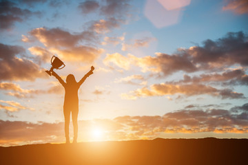 Happy celebrating winning success woman at sunset. Silhouette of