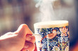 Dampfende Teetasse mit mit kunstvollem Muster gehalten von Männerhand