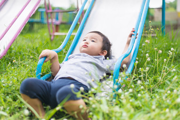 Wall Mural - Little Asian kid playing slide at the playground