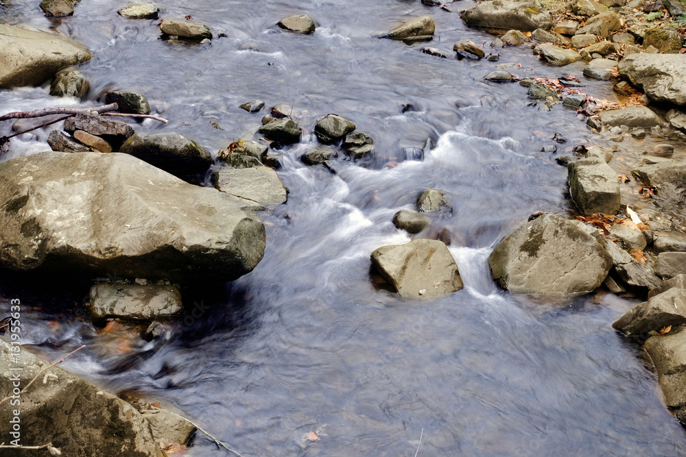 Stream flowing through rocky path in mountains