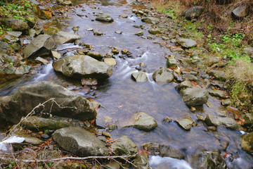 Canvas Print - Stream flowing through rocky path in mountains