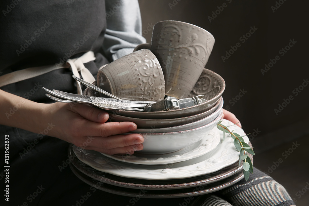 Female hands holding pile of dishware, closeup