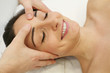 Esthetician massaging head and face of young woman during facial