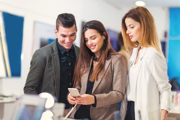 Three people are choosing smart phones in store