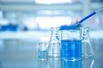 Wall Mural - blue drop into glass beaker with flask and science laboratory