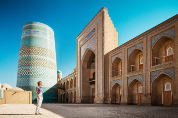 Wall Mural - Young lady taking a picture of oriental buildings in Itchan Kala ancient town. Khiva, Uzbekistan