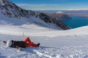 Woman snowboarder laying on snow and enjoy sunlight