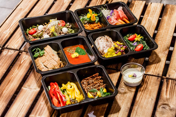 Healthy food and diet concept, restaurant dish delivery. Take away of fitness meal. Weight loss nutrition in foil boxes. Steamed veal with cous and vegetables at wood