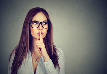 woman saying hush be quiet with finger on lips gesture
