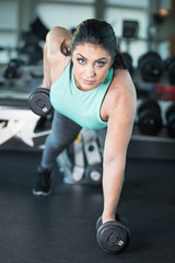 Wall Mural - Pretty woman with blue eyes doing pushups with barbells in gym w