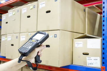 Hands holding portable barcode scanner in warehouse