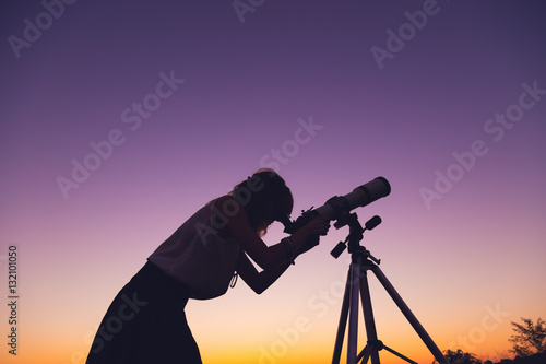 Fotomural Girl looking at the stars with telescope beside her.