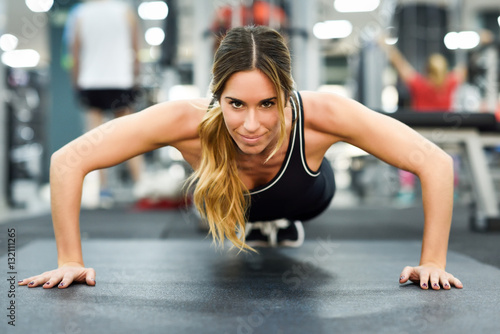 Láminas Young beautiful woman doin pushups in the gym.