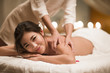 © Blue Jean Images - Masseuse giving a back massage to a woman in a spa