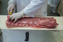 Butcher Cutting Meat At Meat Factory
