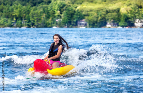 Zdjęcie XXL Szczęśliwa młoda dziewczyna prędkości przez jezioro nadmuchiwane w letni dzień