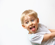 Little Boy Teasing, Showing Tongue And Makes A Face, On White Ba