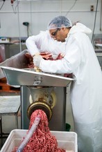 Butchers Placing Meat In Mincing Machine