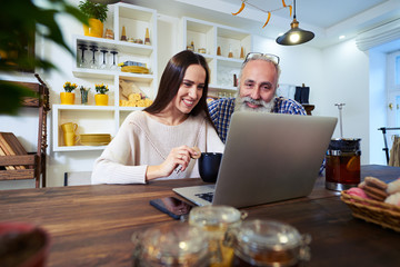 side view of smiling couple looking at the screen of a laptop at