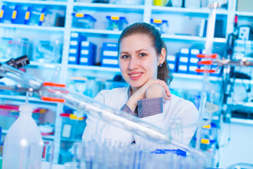 Poster - Attractive young female scientist working in laboratory.  Woman scientist looking at a red test tube in a lab. Young woman in chemical lab