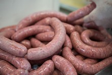 Butcher Processing Sausages In Meat Factory
