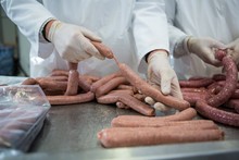 Butchers Processing Sausages At Meat Factory