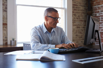 Mature Businessman Working On Computer In Office