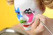 Clown schminkt sich zu Karneval, Fasching oder Fastnacht mit Schminke und Farben