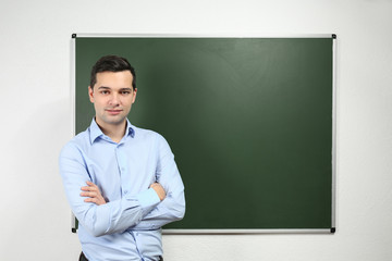 Canvas Print - Handsome young teacher near blackboard in classroom