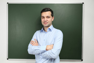 Canvas Print - Handsome young teacher near blackboard in classroom