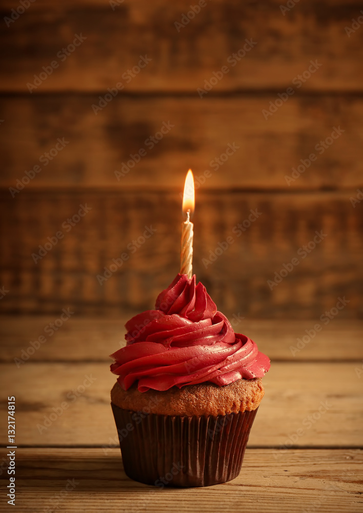 Tasty chocolate cupcake with candle on wooden table