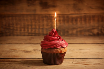 Poster - Tasty chocolate cupcake with candle on wooden table