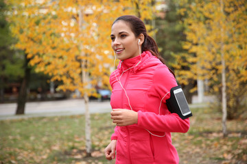 Sticker - Beautiful young woman listening music while running in autumn park