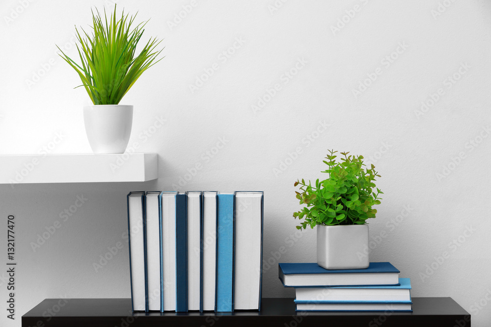 Shelf with new books on light wall background