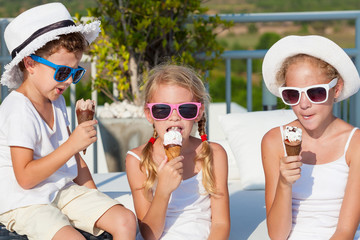 Wall Mural - Three happy children eating ice cream near swimming pool at the