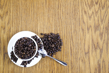 Wall Mural - Cup of coffee in a white cup and coffee beans on wooden table ba