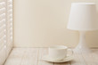 Table lamp with shade and Cup on a light wooden background.