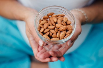 Close Up Of Woman Holding glass bowl with Almonds nuts.