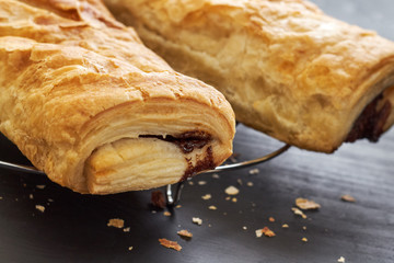 Puff pastry with chocolate filling on black wooden background