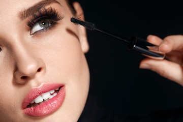 Wall Mural - woman with makeup, long eyelashes applying mascara. doing makeup