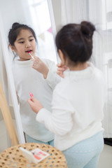 Wall Mural - Pretty Asian child doing make up front of the mirror