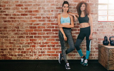 Wall Mural - Two young women standing by wall in gym