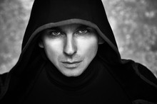 Mysterious Man In Black Hoodie. Sexy Hero Guy. Pastor Or Wizard In Robe. Assassin Or Witcher With Strong Face Expression In Cloak. Dark Magician Black And White Photo. Fantasy Book Cover Concept.