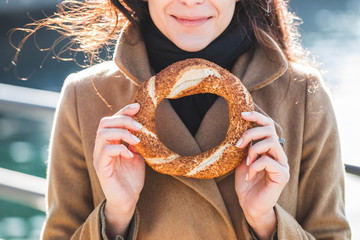 Wall Mural - Beautiful woman holds a traditional Turkish simit in hands and w