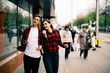 © dashamuller - Two happy trendy teenage friends walking and dancing in the city, listening to the music with headphones, talking each other and smiling. Lifestyle, friendship and urban life concepts.