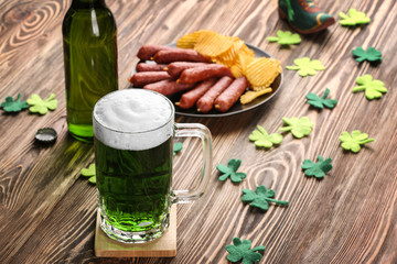 Canvas Print - St. Patrick Day concept. Glass of green beer and plate with crisps and sausages on wooden table