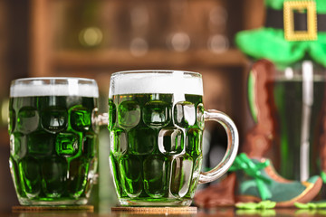 Poster - St. Patrick Day concept. Glasses of green beer on bar counter and blurred background