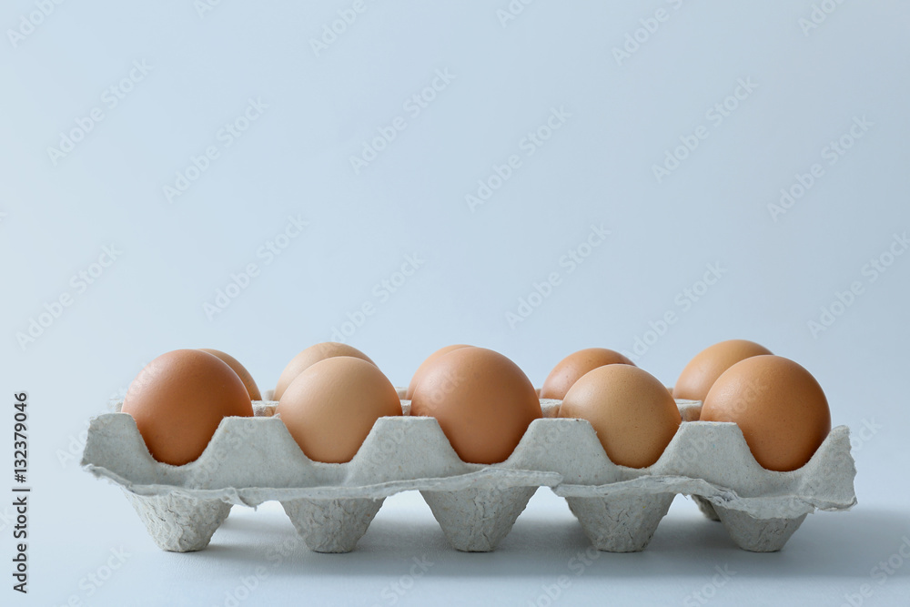 Raw eggs in package on white background