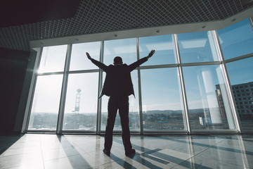 Business man celebrate victory and success in work alone against panoramic windows