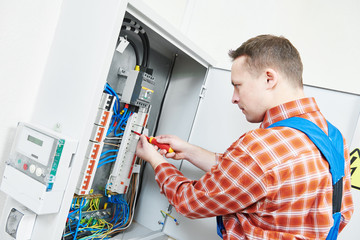 electrician works with electric meter tester in fuse box